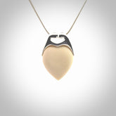 This picture shows a pendant that we have carved in a combination of sterling silver and woolly mammoth. It shows a symbolic kiss, with two heads coming together and both embracing a woolly mammoth heart. The necklace is a sterling silver chain.